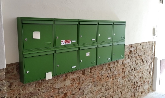 Zelené panelákové schránky v sestavě.